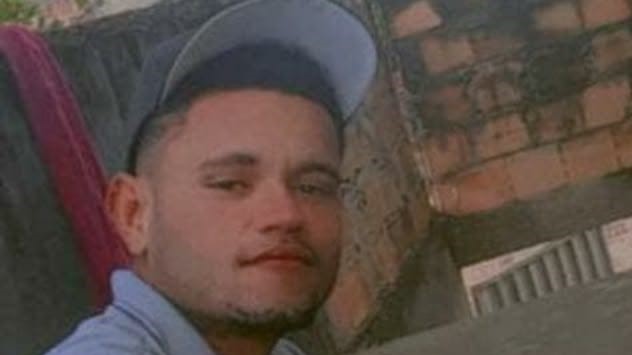 Jovem de boné e camisa branca em uma casa sem reboco
