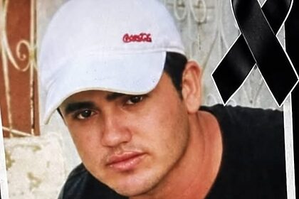 Homem sério de boné branco com uma faixa de luto